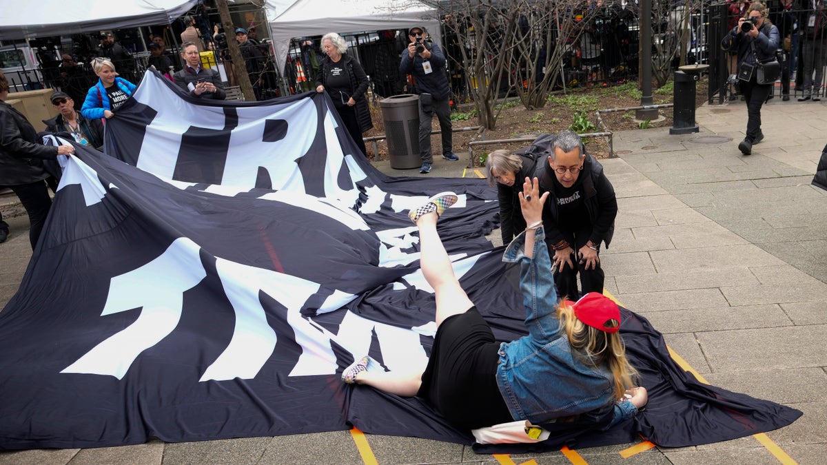 NEW YORK, NEW YORK - APRIL 04: A supporter of former U.S. President Donald Trump tumbles to the ground on top of a banner criticizing him outside the courthouse where Trump will arrive later in the day for his arraignment on April 4, 2023 in New York City. With his indictment, Trump will become the first former U.S. president in history to be charged with a criminal offense. (Photo by Drew Angerer/Getty Images)