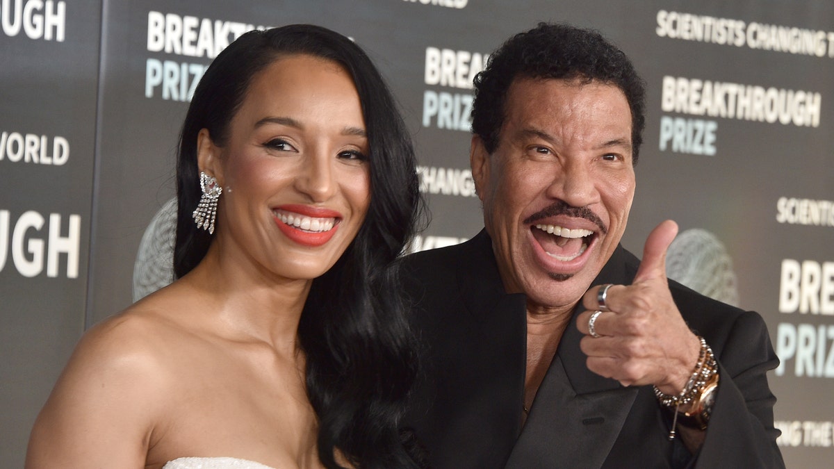 Lionel Richie gives thumbs up alongside his wife.