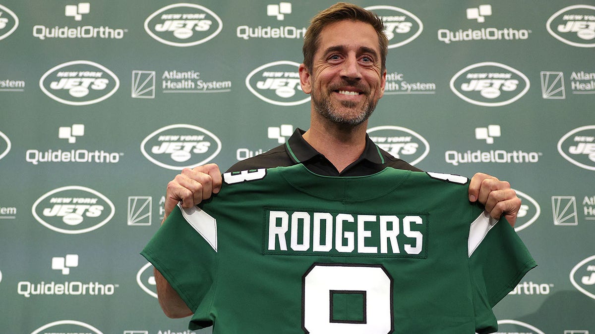 Aaron Rodgers poses with a Jets jersey