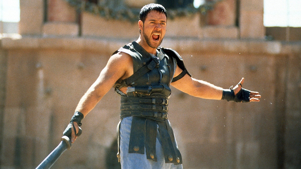 Russel Crowe yells with body armor on holding a sword in a scene from "Gladiator"
