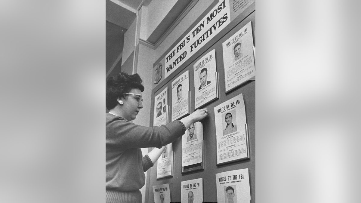 Receptionist Betty Porco keeps 10 Most Wanted pictures straight in Denver FBI office.