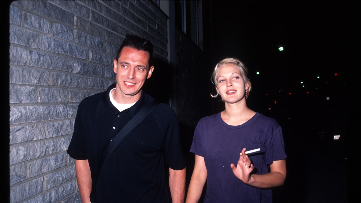 Drew Barrymore with bleach blonde hair holding hands with Jeremy Thomas