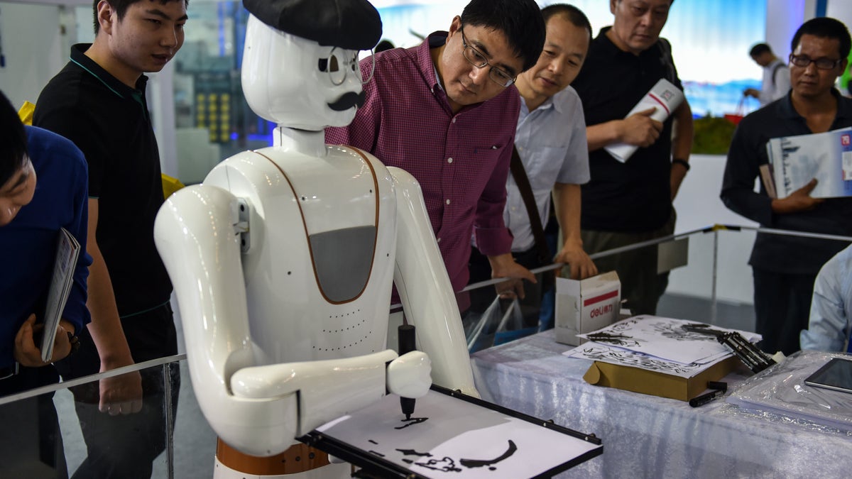 Onlookers observe as a robot paints an image in Shenzhen, China, on Nov. 16, 2017.