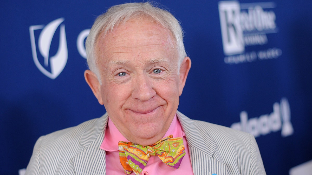 Leslie Jordan in a pink shirt, orange, green and yellow bow-tie and a seersucker jacket on the red carpet
