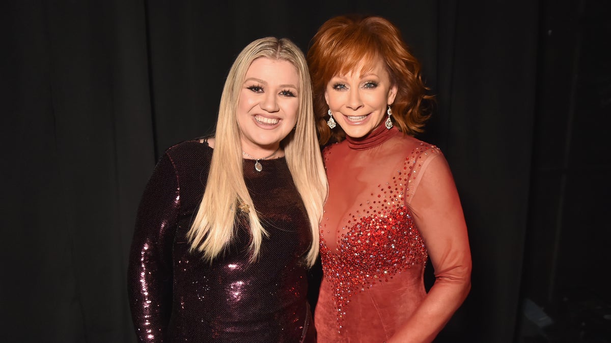 Kelly Clarkson in dark red sequins with Reba McEntire in sheer red dress