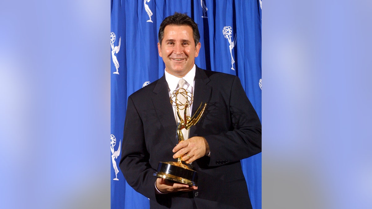 Anthony LaPaglia in a suit holding his Emmy