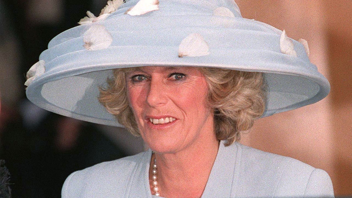 Camilla Parker Bowles in a blue dress with an oversized matching hat adorned with flowers
