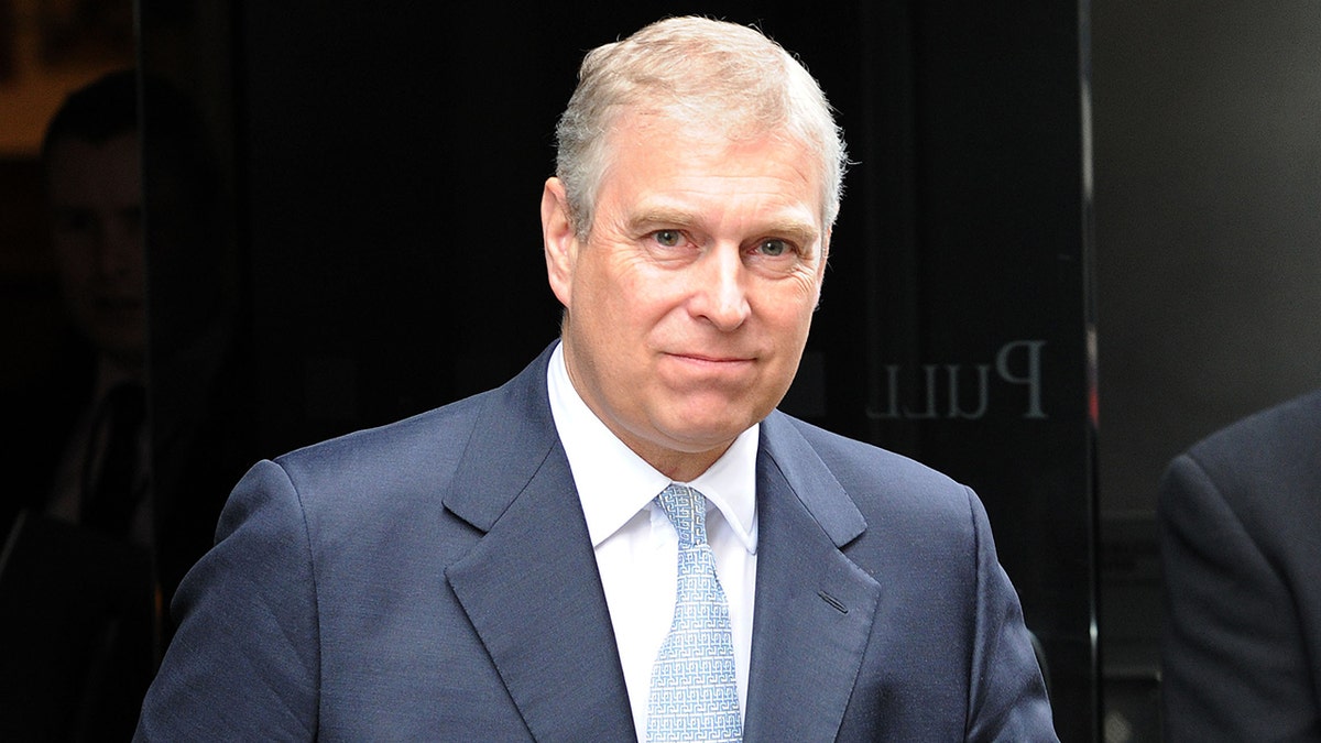 Prince Andrew wearing a navy suit and a white shirt with a light blue tie