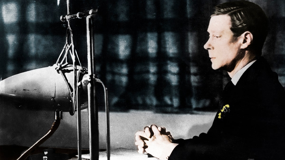 Edward VIII speaking to a mic while wearing a suit and sitting down