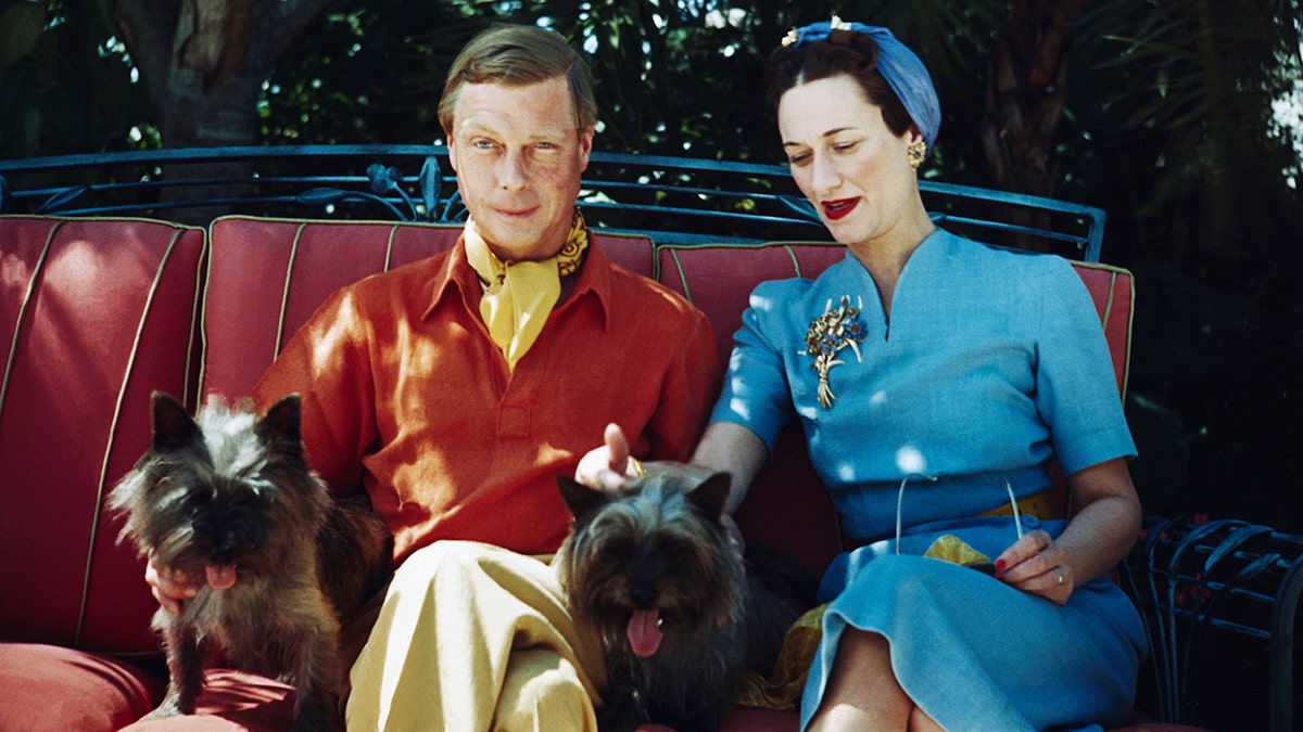 Edward VIII wearing a red shirt and khacki pants with Wallis Simpson wearing a bright blue dress