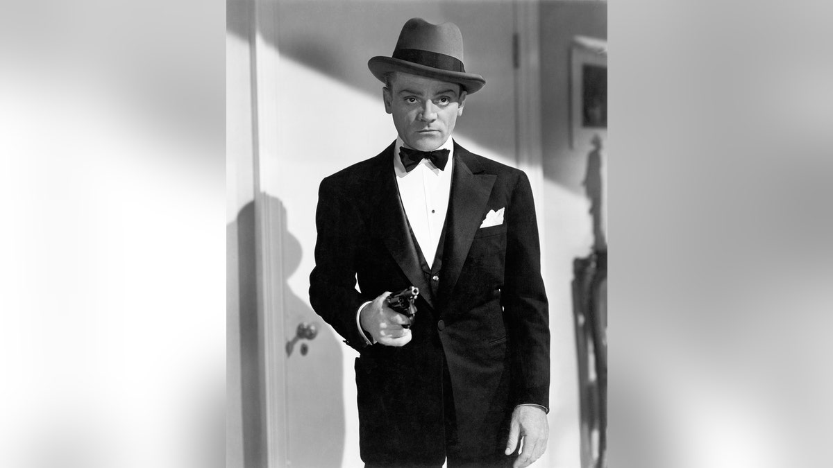 James Cagney in a suit and bow tie with a fedora holding a gun