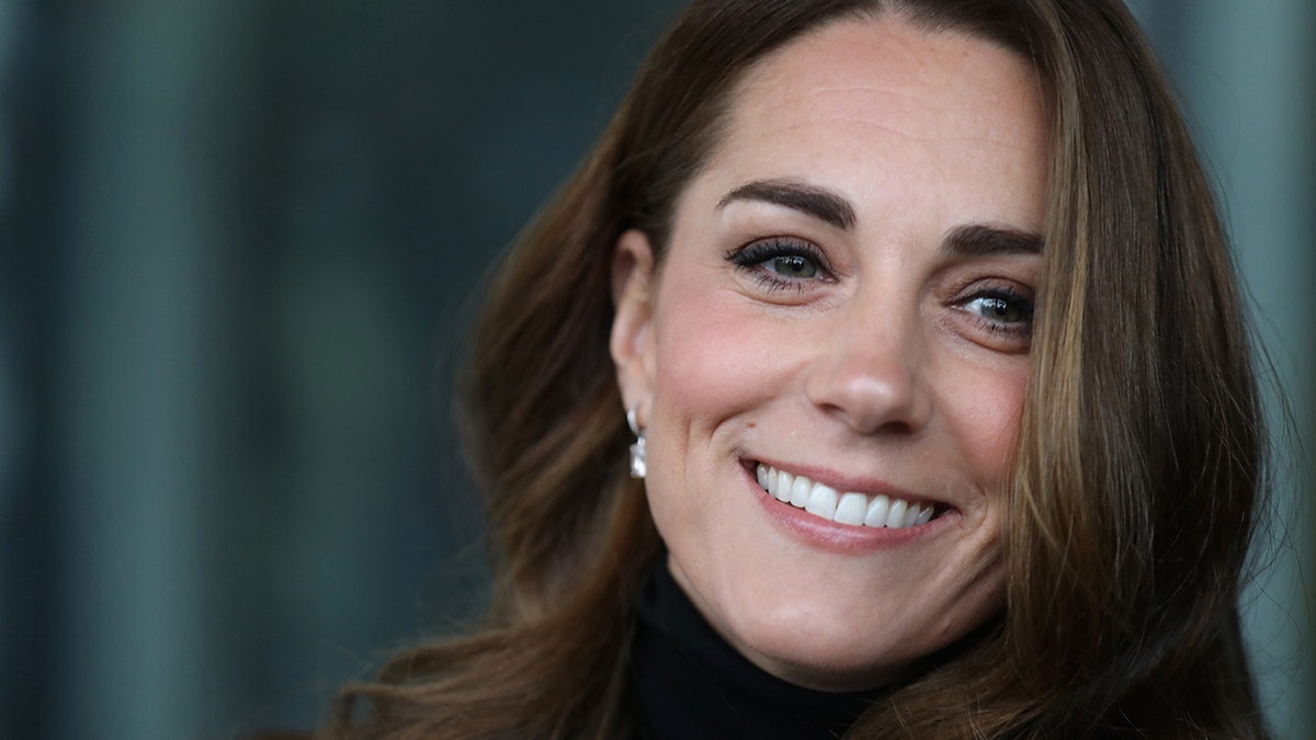 A close-up of Kate Middleton smiling wearing a black turleneck