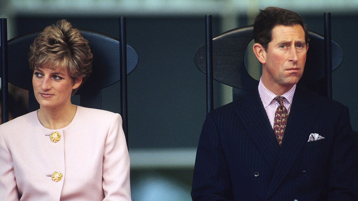 Princess Diana wearing a pink blazer top next to Charles in a suit and tie