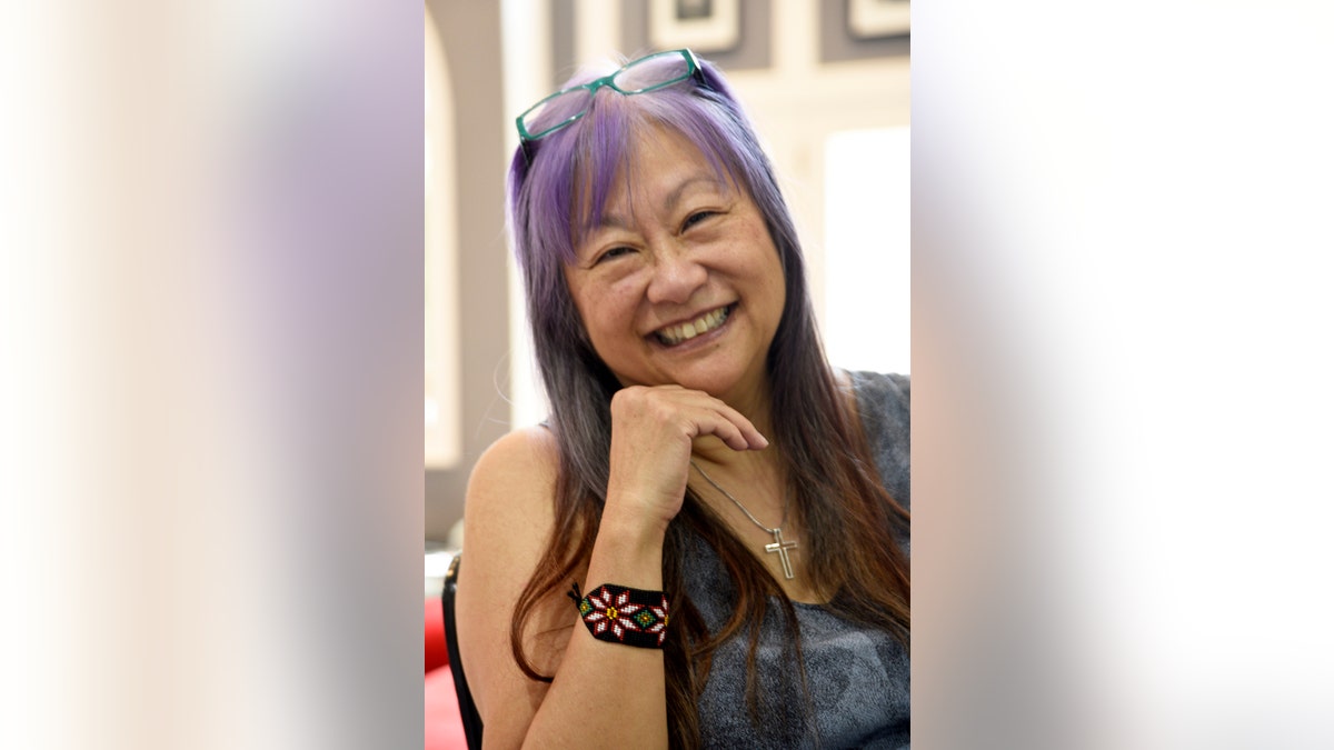 May Pang smiling with purple hair