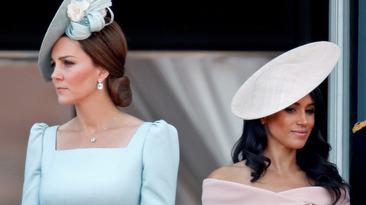 Kate Middleton wearing a light blue dress next to Meghan Markle wearing a pink dress