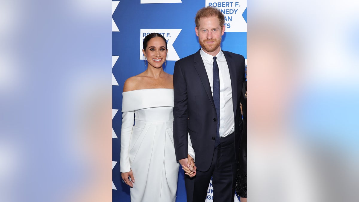 Meghan Markle wearing a white dress next to Prince Harry in a suit and tie
