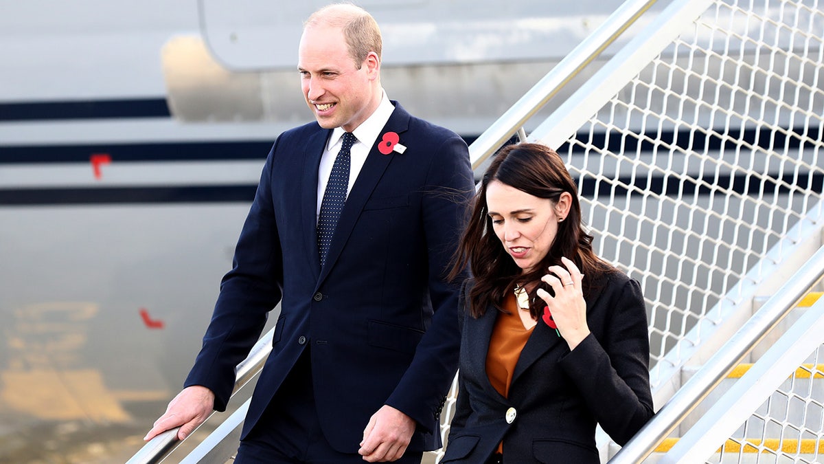 Prince William and Jacinda Ardern wearing dark outfits while exiting a terminal