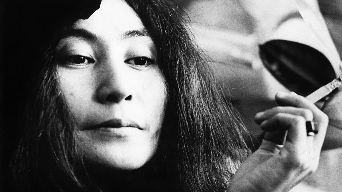 A close-up of Yoko Ono holding a cigarette