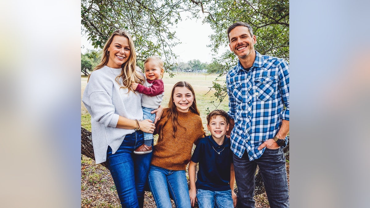 Granger Smith, his wife and their three children posing outside for a family photo