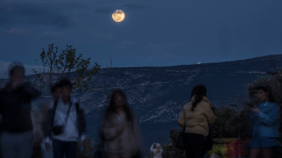A woman takes a photo of the pink moon in Athens, Greece