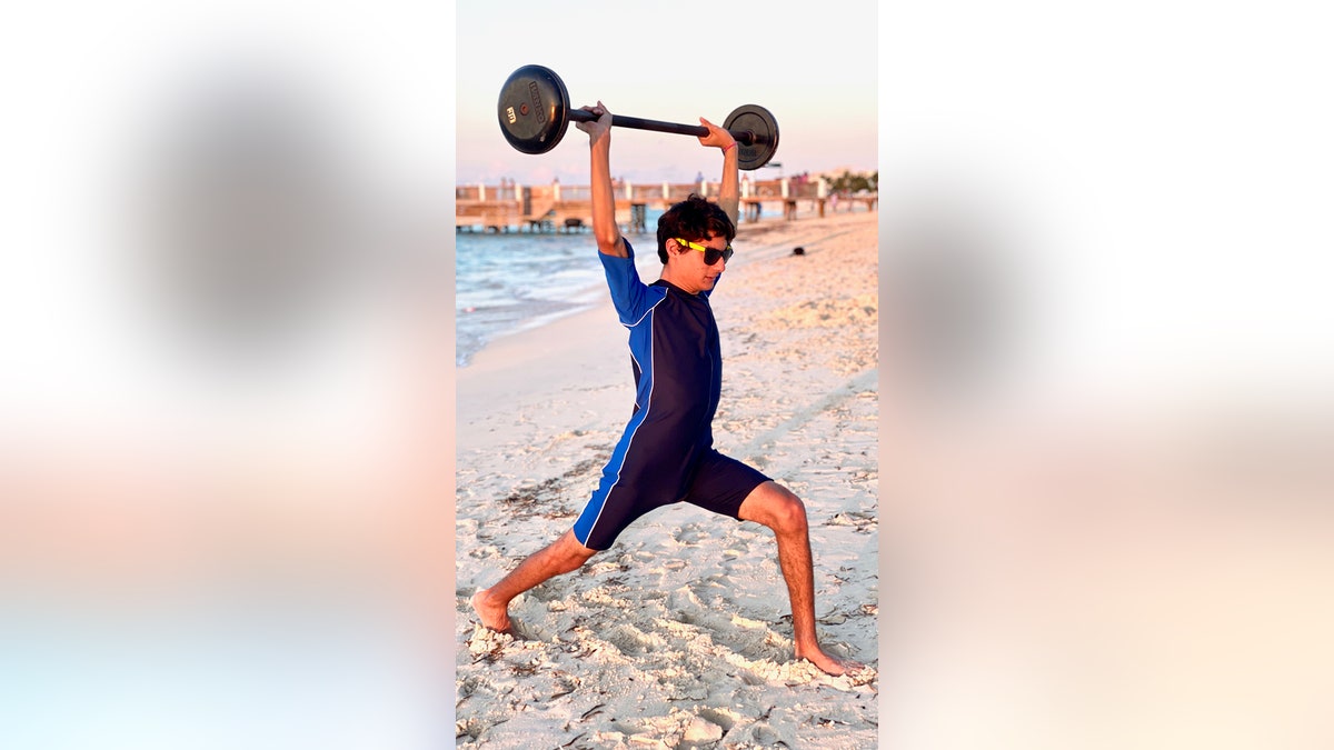 Heather Arak son lifting weight on beach