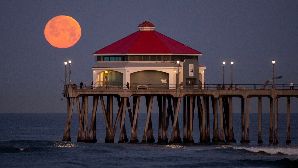 The pink moon over a Huntington Beach, Calif. pier