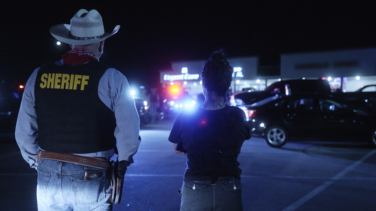 Roo Powell standing next to a sheriff at night