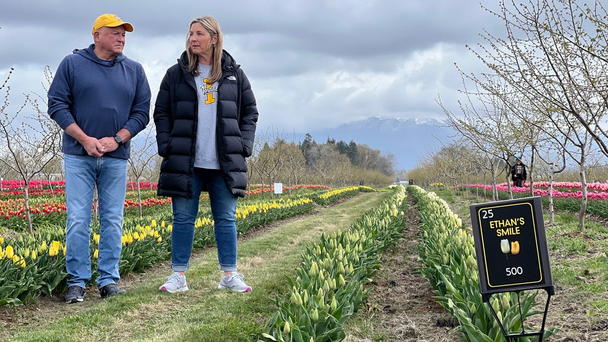 Ethan Chapin's parents standing near rows of flowers