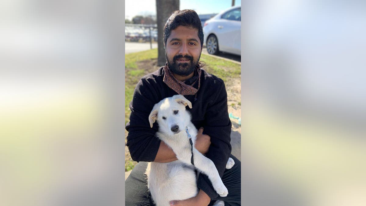 Jason John holds a white dog