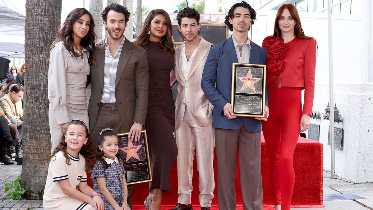 The Jonas Brothers and their families taking a photo at the walk of fame.
