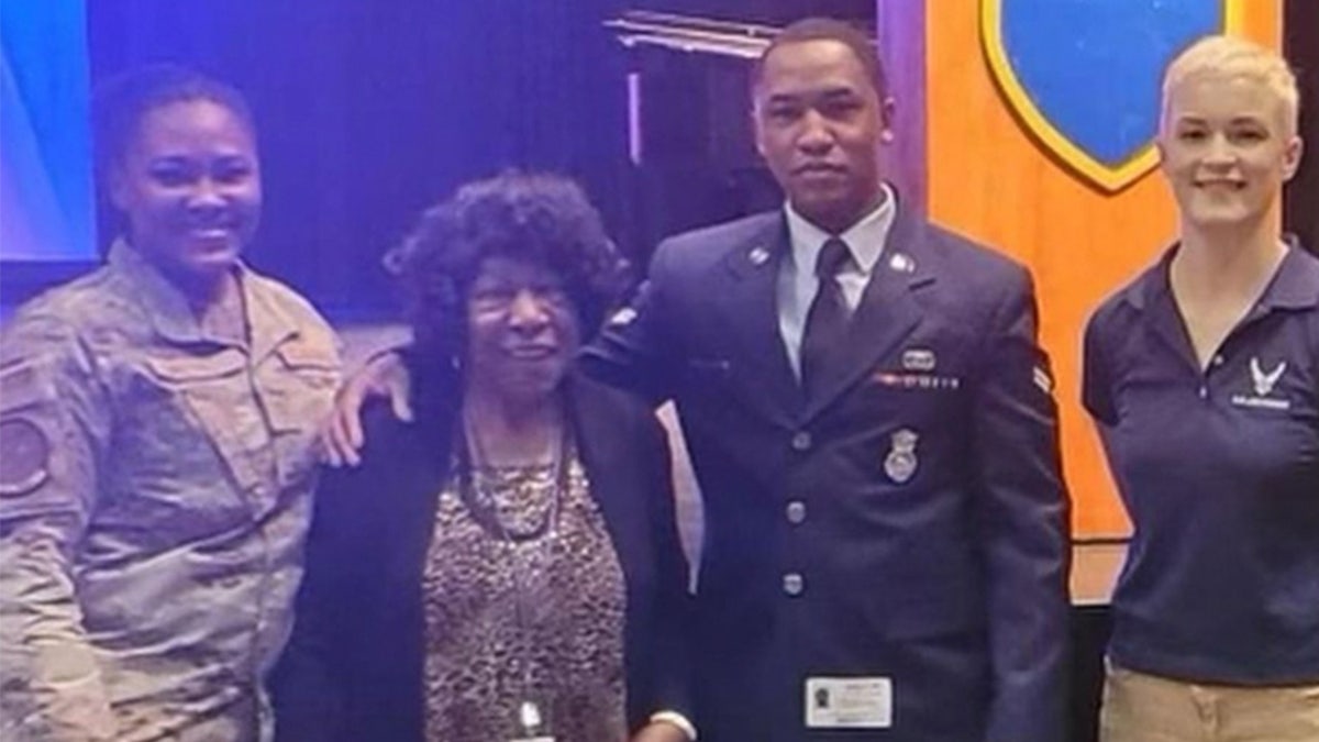 Dayvon Johnson poses in uniform with three people.
