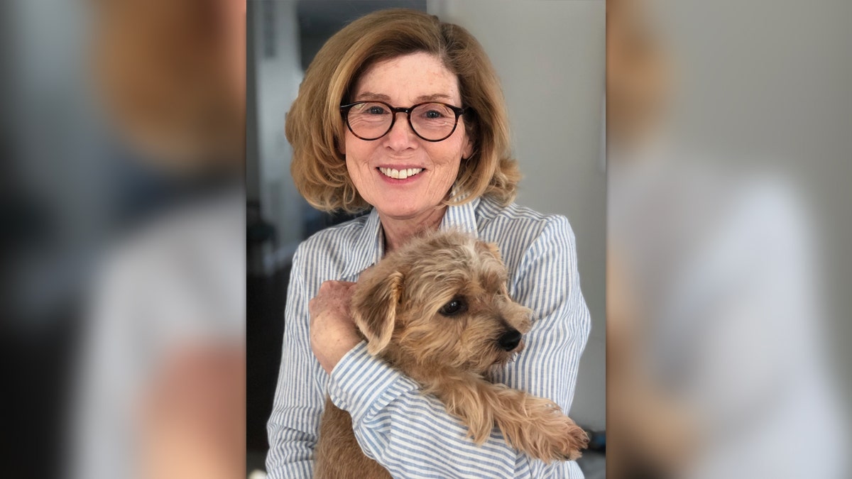 Maria wearing glasses and striped shirt holds her dog