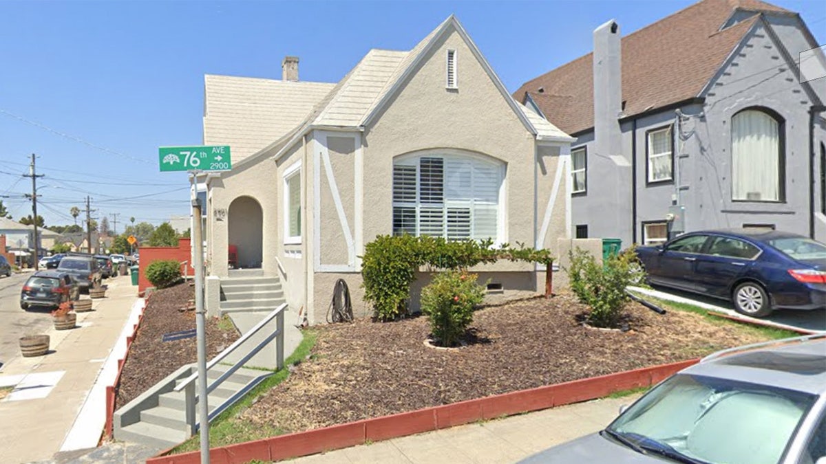 A creme-colored hom with a pointe roof next to a gray home in Oakland, California.