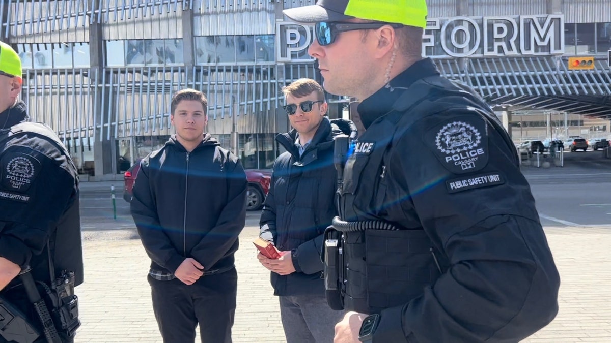 Nathaniel Pawlowski and Declan Friesen standing with an officer