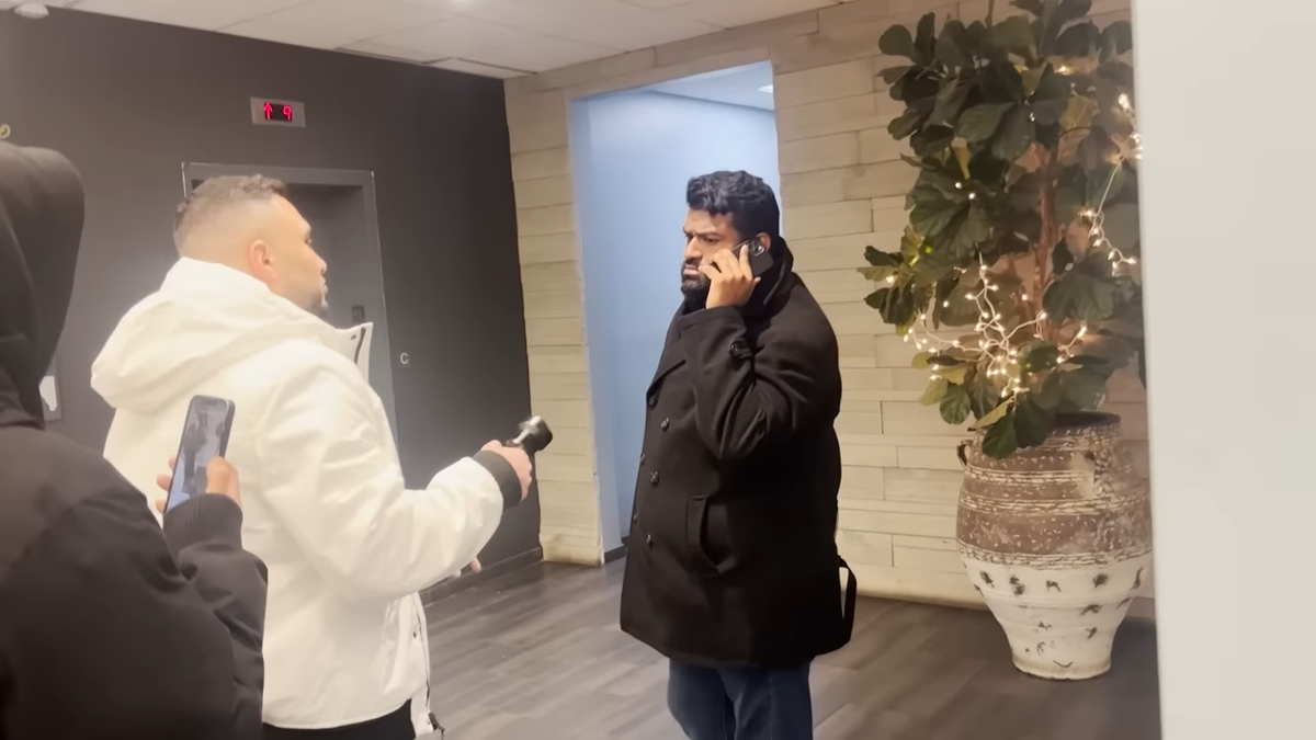 Anand Singh talking into cellphone while approached by reporter