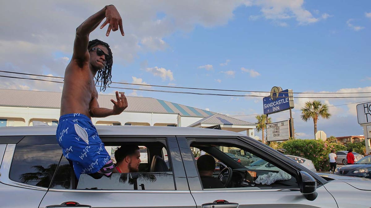 A party goer leaning out of his cars window during stopped traffic at Orange Crush