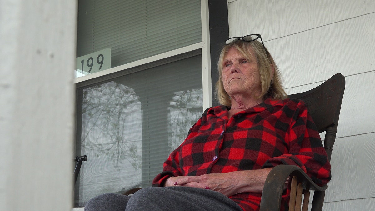 Woman sits in chair on porch