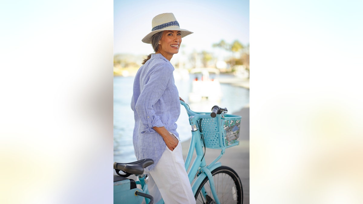 Nina Cash wearing a light blue and white pants with a matching hat on a light blue bike