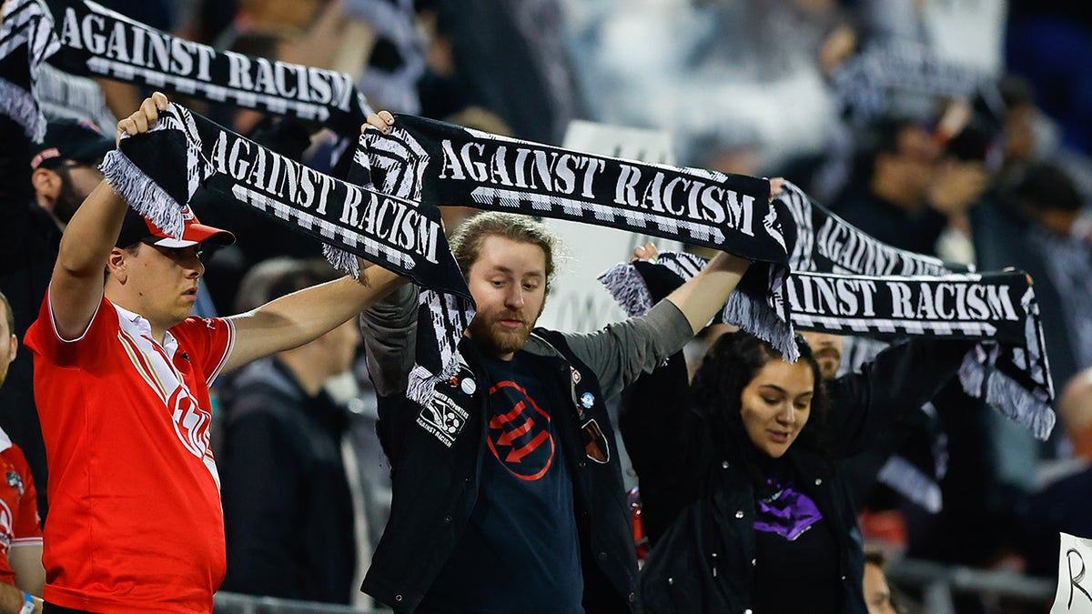 Supporters hold up 'against racism' scarves