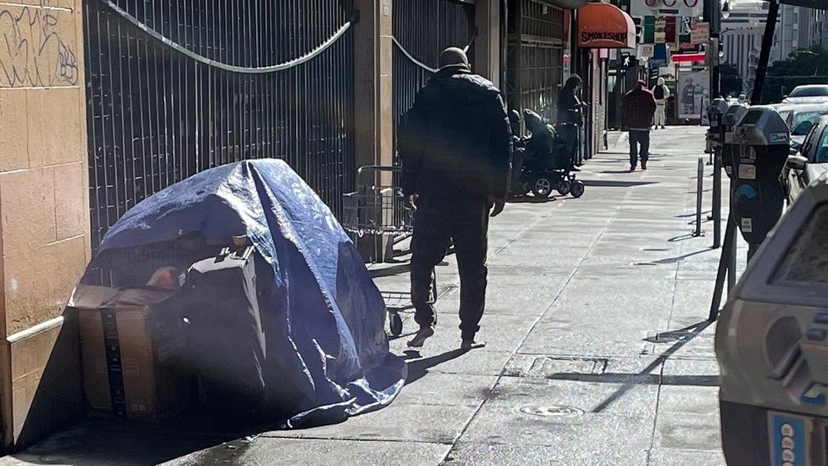 Barefoot man near homeless encampment on SF sidewalk