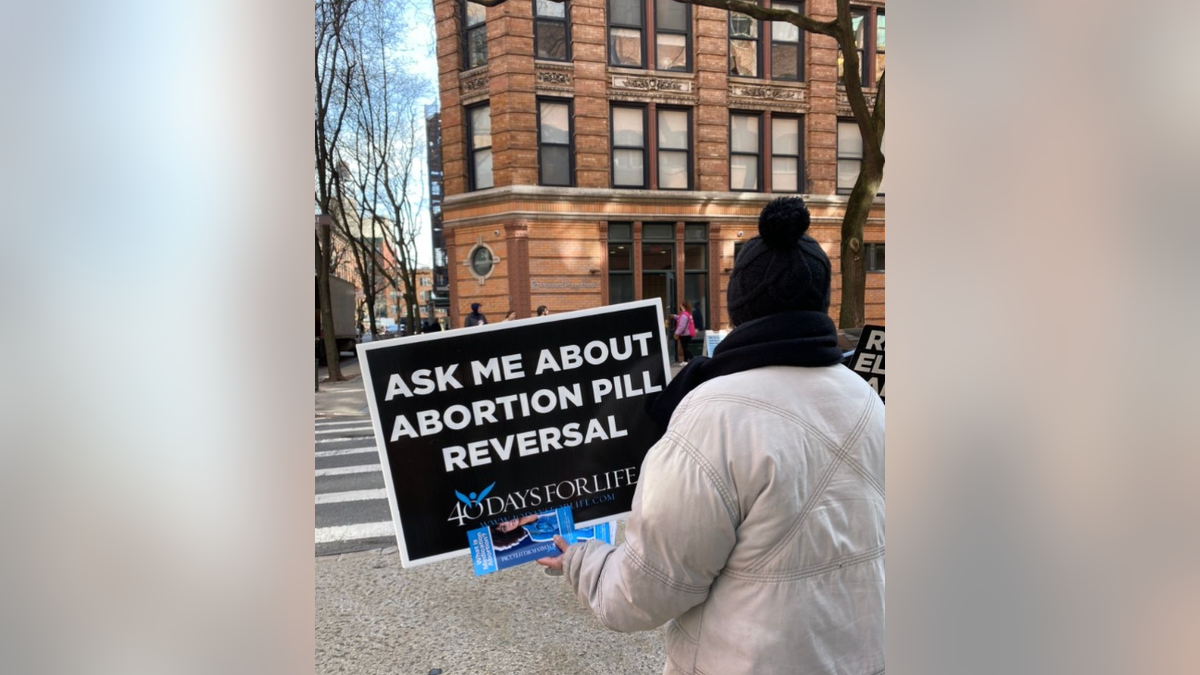 Abortion protester holding sign about abortion pill reversal