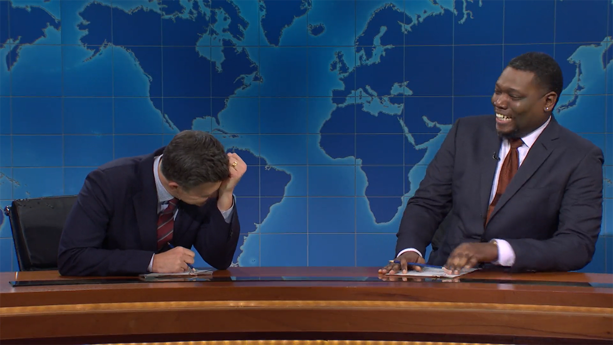 Colin Jost puts his hand to his forehead laughing while Michael Che laughs as he realizes he was pranked during "SNL's Weekend Update"