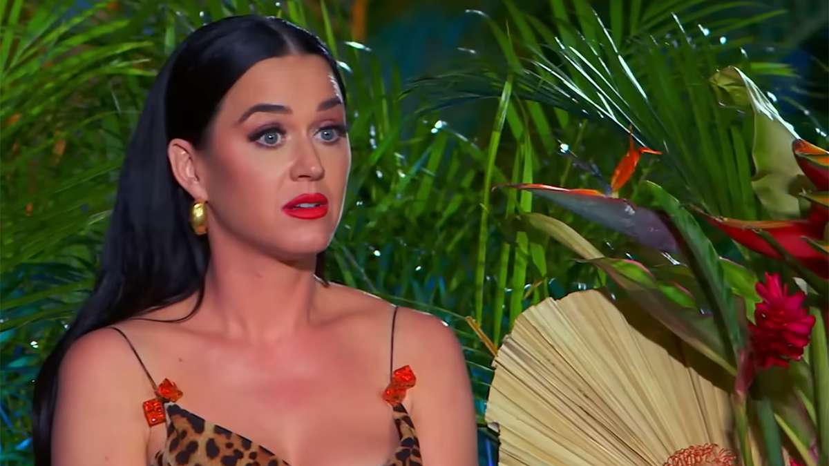 Katy Perry in a cheetah print tank top with red bows looks perplexed while watching a performance during "American Idol"