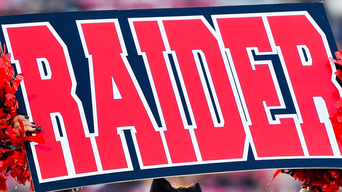 Cheerleader holds up a Raider sign