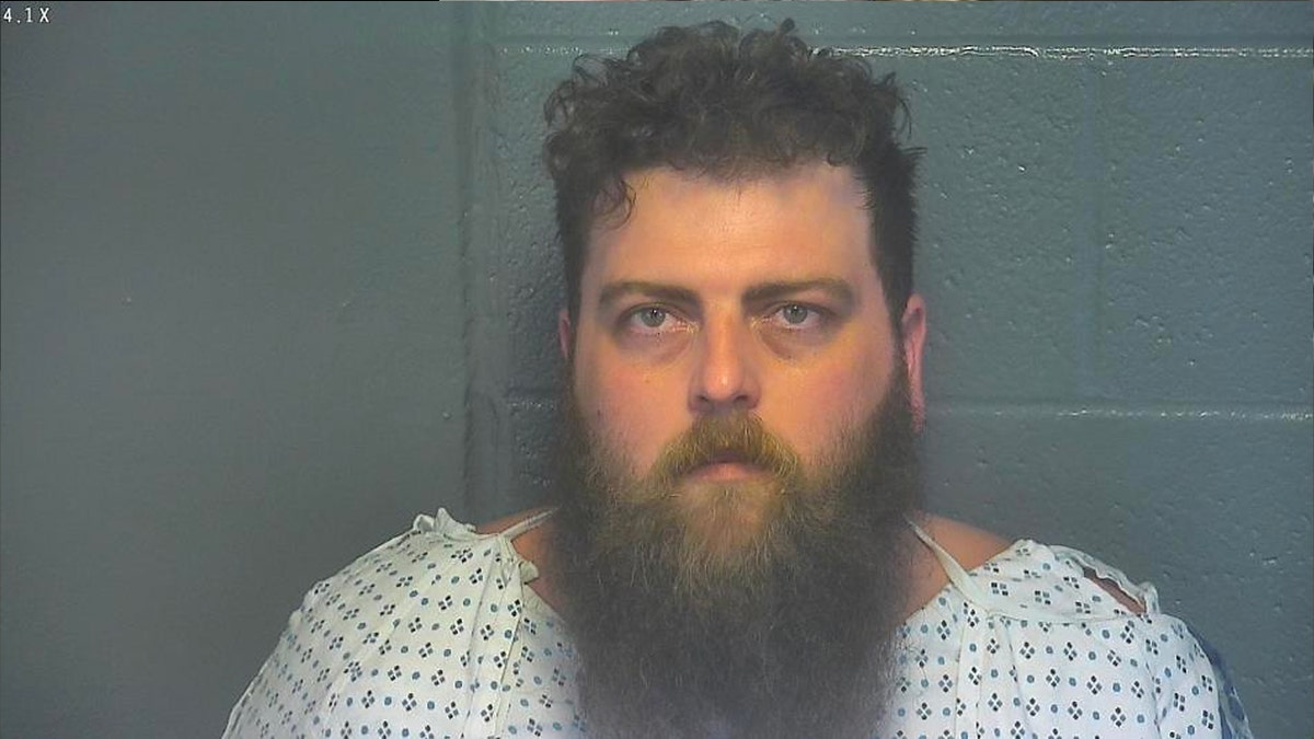 Tyler Myers has long beard, wearing hospital gown in mug shot