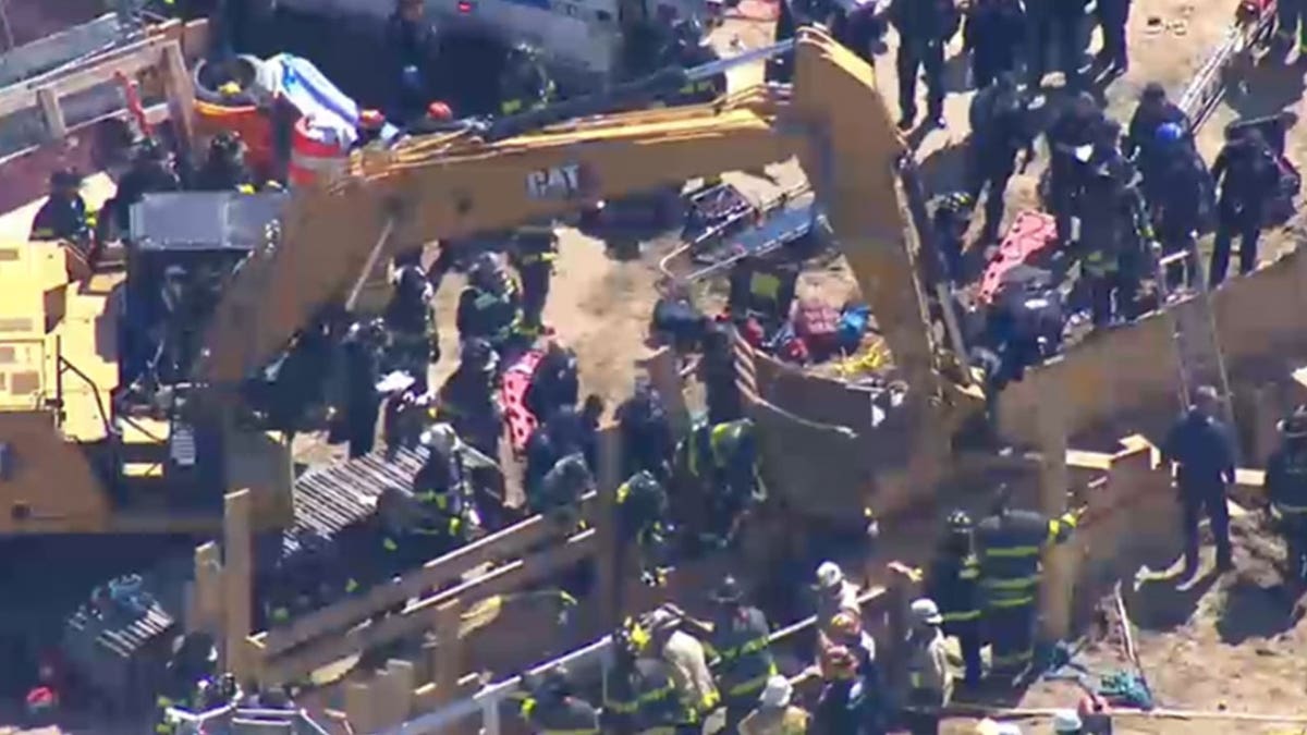 First responders surrounding a crane near a trench.