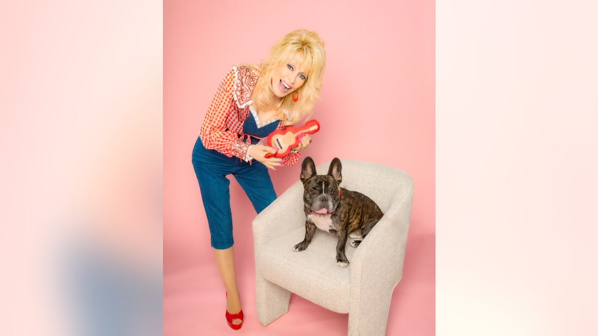Dolly Parton takes a cute photo while a dog sits beside her in a chair.
