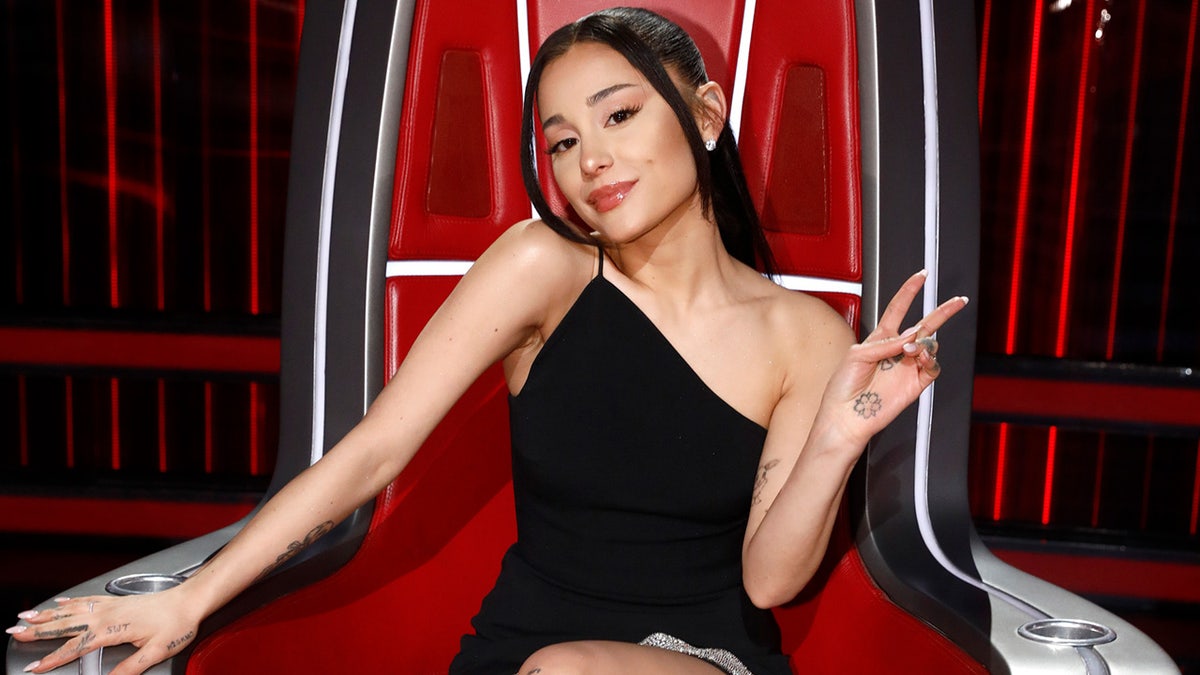 Ariana Grande flashes a peace sign while judging The Voice