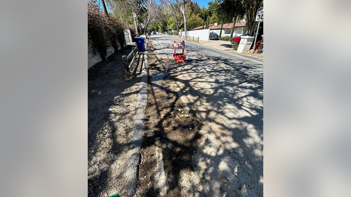 View of two potholes and a hazard sign next to the first pothole