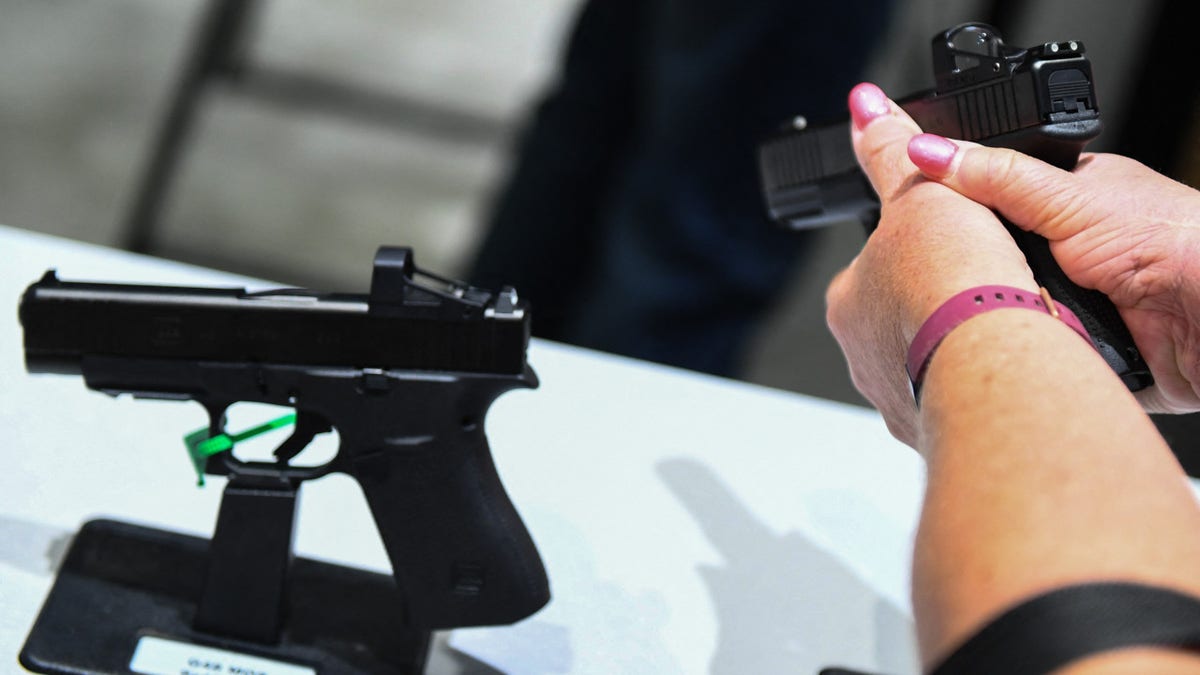 woman holds handgun at display case